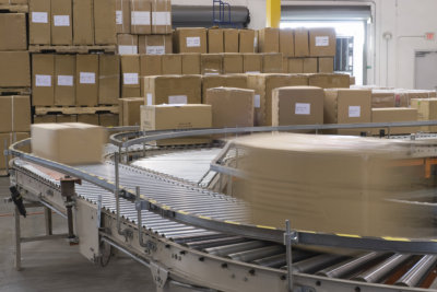 Cardboard boxes on conveyor belt in distribution warehouse